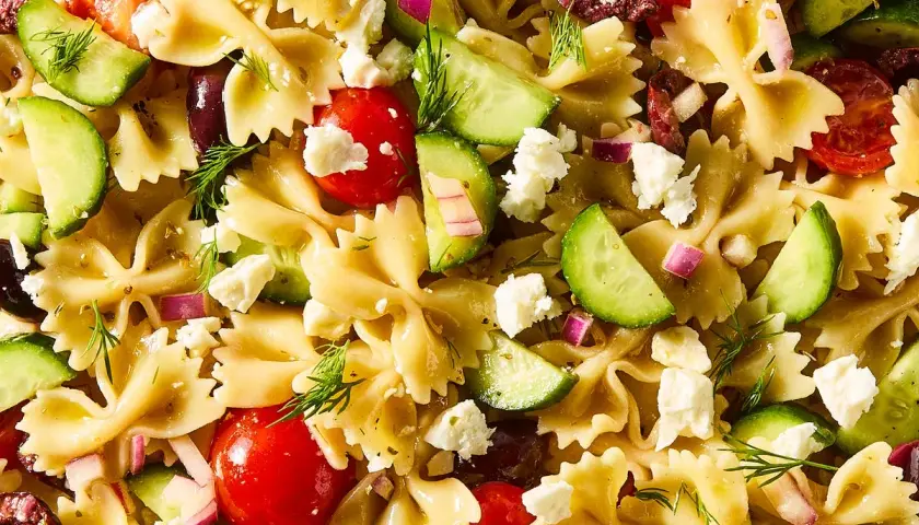 Ensalada de pasta con lazos, tomates cherry, pepino, queso feta, aceitunas y eneldo. ¡Una deliciosa pasta con verduras!