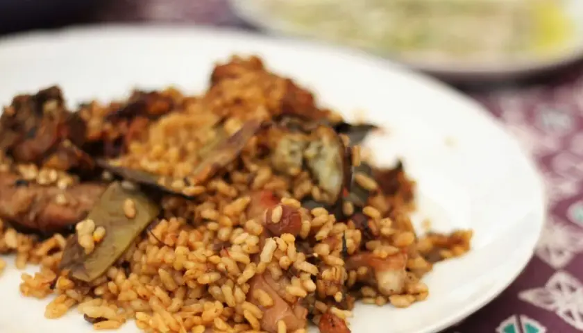 Un plato de arroz con conejo, cocinado a la perfección, con trozos de carne dorada y verduras.