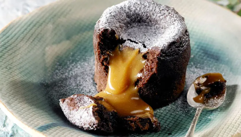Coulant de chocolate con corazón líquido de caramelo, espolvoreado con azúcar glas. Un bocado irresistible.