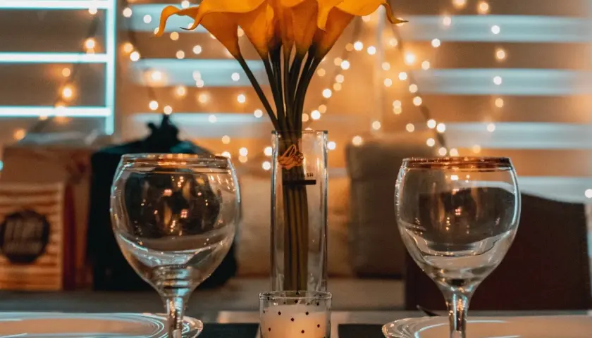Dos copas, un jarrón con calas amarillas y una vela crean el ambiente perfecto para una velada romántica en casa.