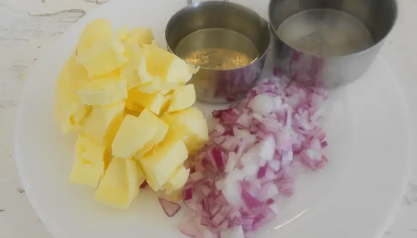 Ingredientes para un clásico beurre blanc: mantequilla en cubos, cebolla morada picada y dos recipientes con líquido.