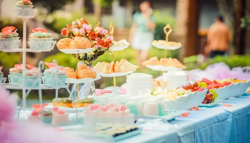 Deliciosa merienda baby shower con cupcakes, bollos, sándwiches y fruta fresca.