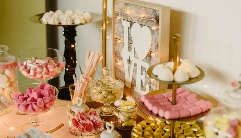 Mesa dulce con dulces variados, malvaviscos, caramelos y un cartel de "LOVE". Un candy bar original para celebrar el amor.