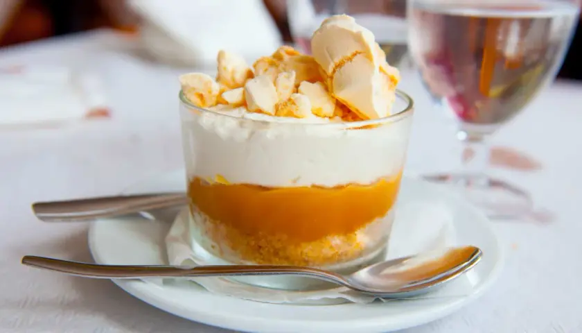 Delicioso postre en vaso con capas de galleta, dulce de leche y crema, coronado con merengue crocante. Un polvito uruguayo que invita a disfrutar.
