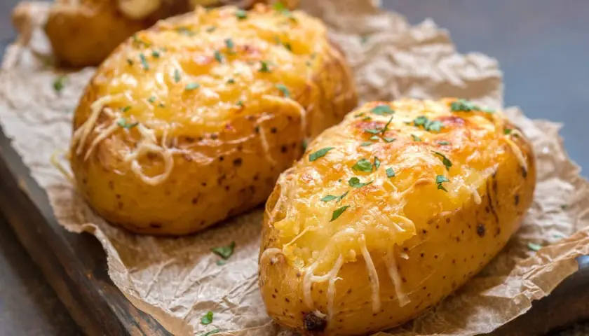 Patatas panaderas doradas y gratinadas con queso, espolvoreadas con perejil fresco.