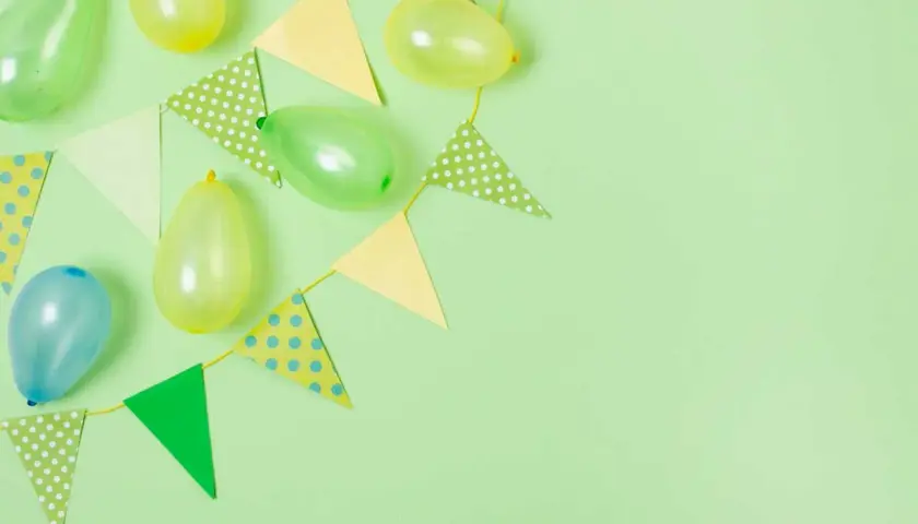 Globos y banderines de colores pastel sobre fondo verde claro, perfectos para ideas de cumpleaños.