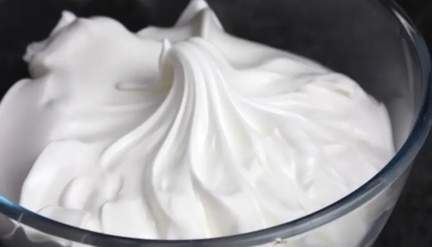 Merengue italiano esponjoso y brillante en un bol de cristal, listo para decorar postres.