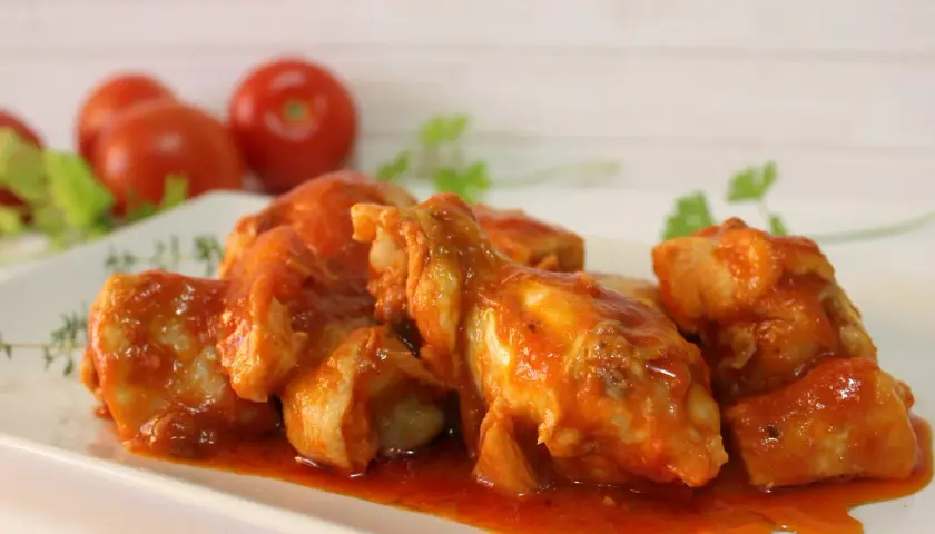 Sabroso pollo con tomate, cocinado a fuego lento hasta que esté tierno y jugoso, servido en una salsa roja vibrante.