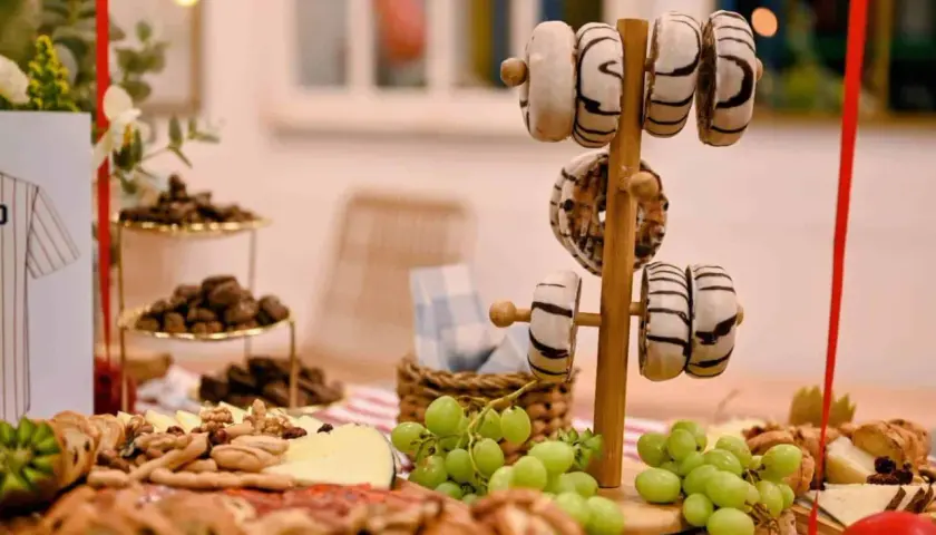 Delicioso picoteo de cumpleaños infantil con donuts, uvas, quesos y frutos secos. ¡Una mesa dulce para celebrar!