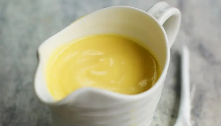 Crema amarilla y sedosa en una salsera blanca, lista para realzar cualquier plato. Es la clásica salsa holandesa.