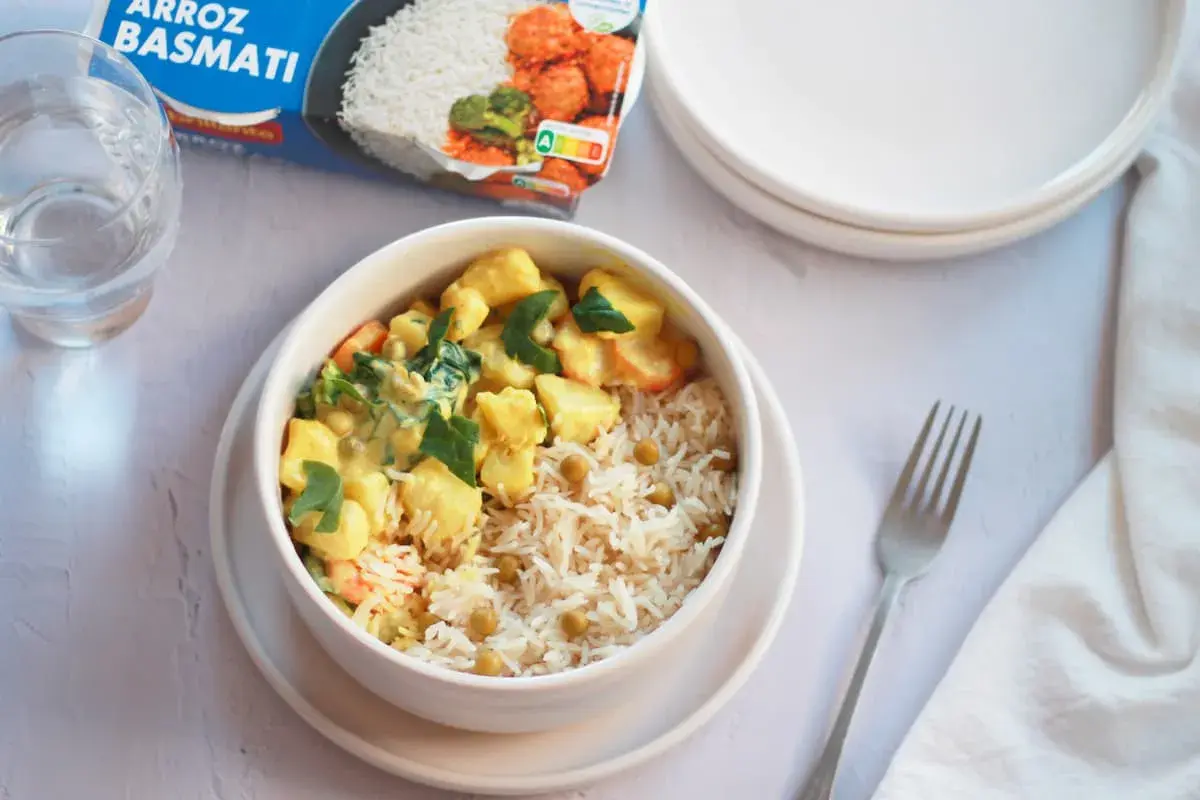 Un tazón de arroz basmati con guisantes y un curry cremoso de verduras, listo para disfrutar.