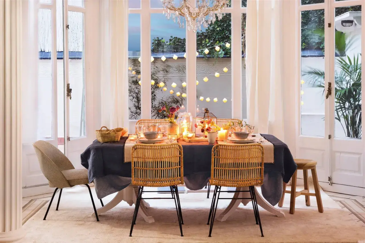 Elegante mesa puesta con velas y luces, perfecta para ideas para cumpleaños adultos en casa.