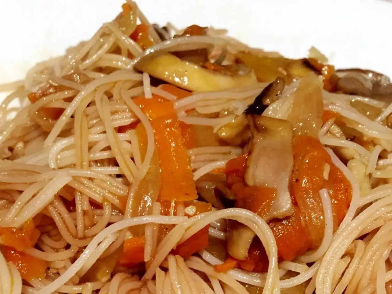 Un plato de fideos de arroz salteados con zanahoria y champiñones, un festín para los sentidos.