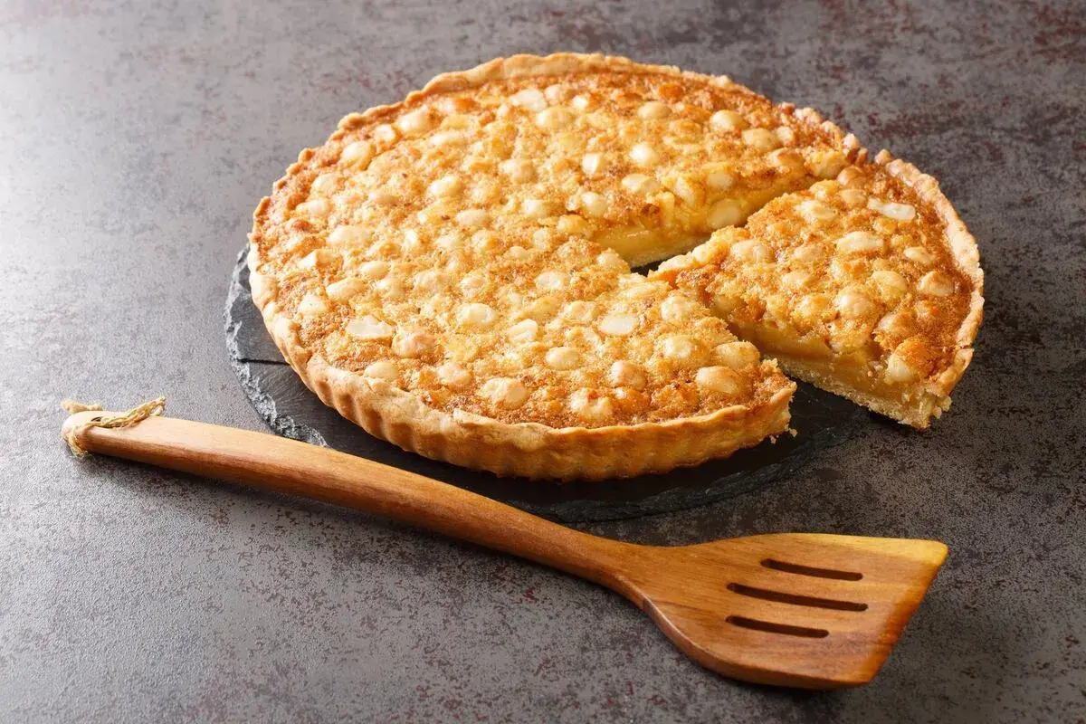 Tarta dorada con nueces sobre base de masa quebrada, lista para servir. Perfecta para tus recetas con masa quebrada.