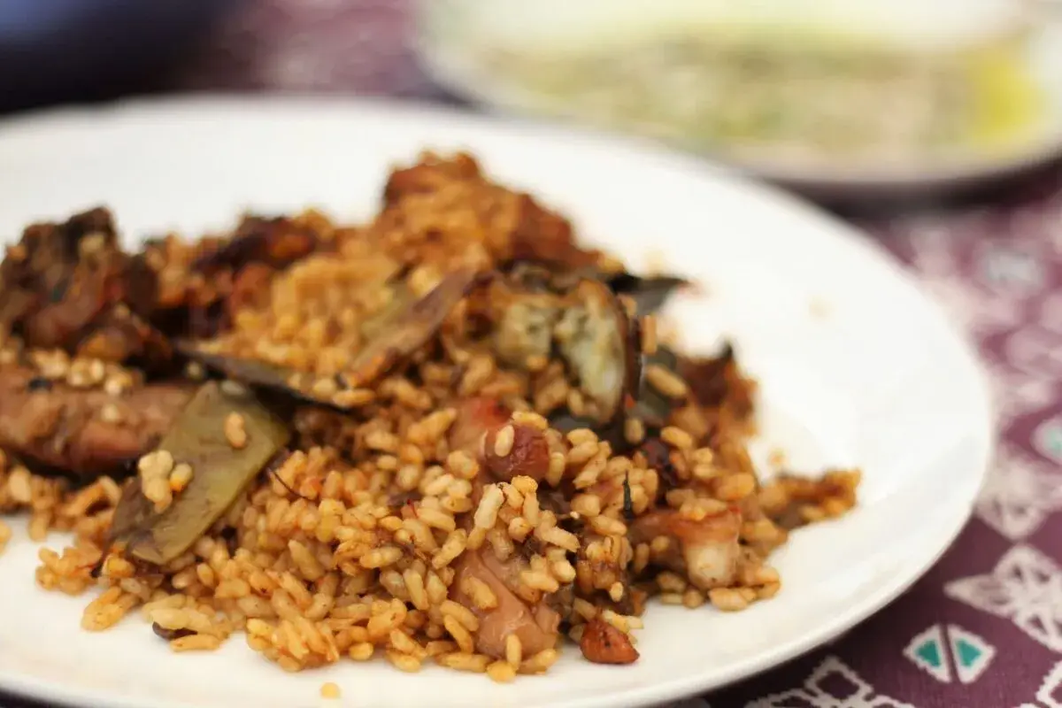 Un plato de arroz con conejo, cocinado a la perfección, con trozos de carne dorada y verduras.