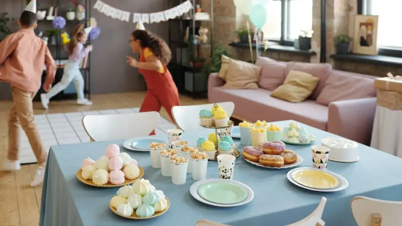 Niños corriendo en fiesta infantil. Mesa con pastel, donas, cupcakes y dulces. ¡Una guía perfecta de como organizar un cumpleaños infantil!