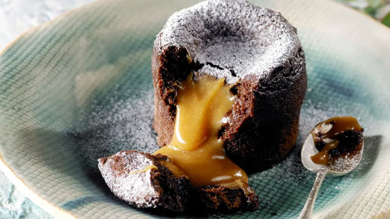 Coulant de chocolate con corazón líquido de caramelo, espolvoreado con azúcar glas. Un bocado irresistible.