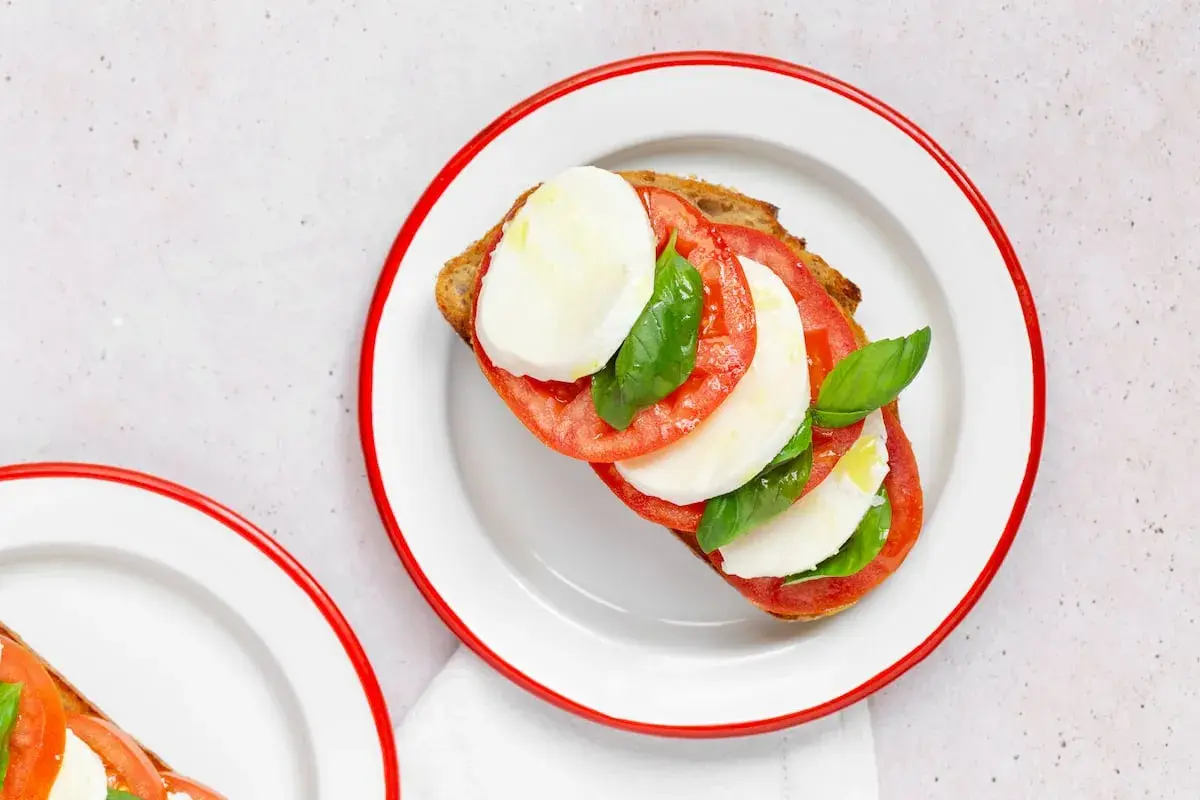 Tostada con rodajas de tomate, mozzarella fresca y albahaca, un clásico de la ensalada caprese.