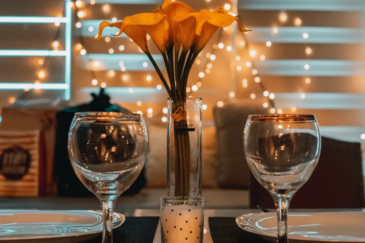Dos copas, un jarrón con calas amarillas y una vela crean el ambiente perfecto para una velada romántica en casa.