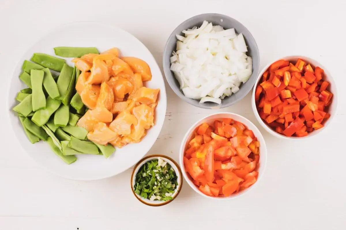 Ingredientes para fideuá de pollo: trozos de pollo, judías verdes, cebolla, pimiento rojo, tomate y perejil picado.