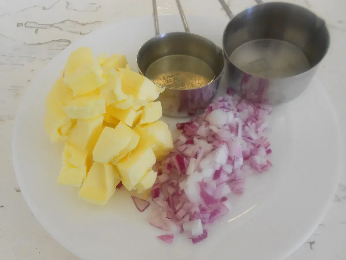 Ingredientes para un clásico beurre blanc: mantequilla en cubos, cebolla morada picada y dos recipientes con líquido.