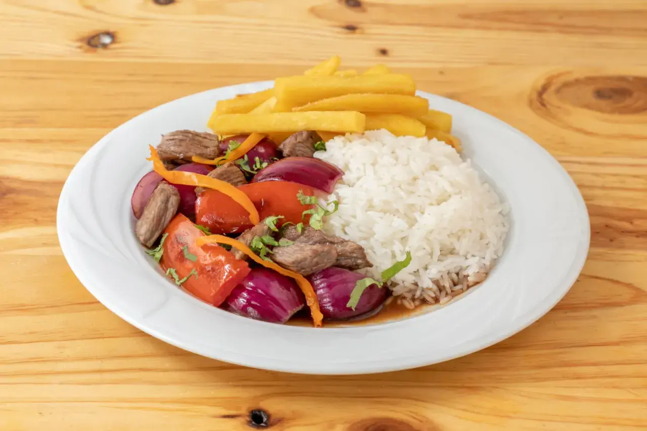 Lomo saltado con arroz blanco, papas fritas, carne, cebolla roja, tomate y cilantro. Un plato peruano delicioso.