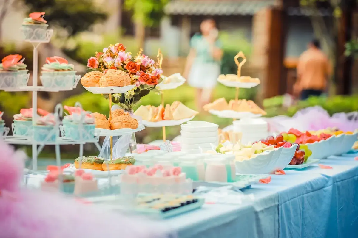 Deliciosa merienda baby shower con cupcakes, bollos, sándwiches y fruta fresca.
