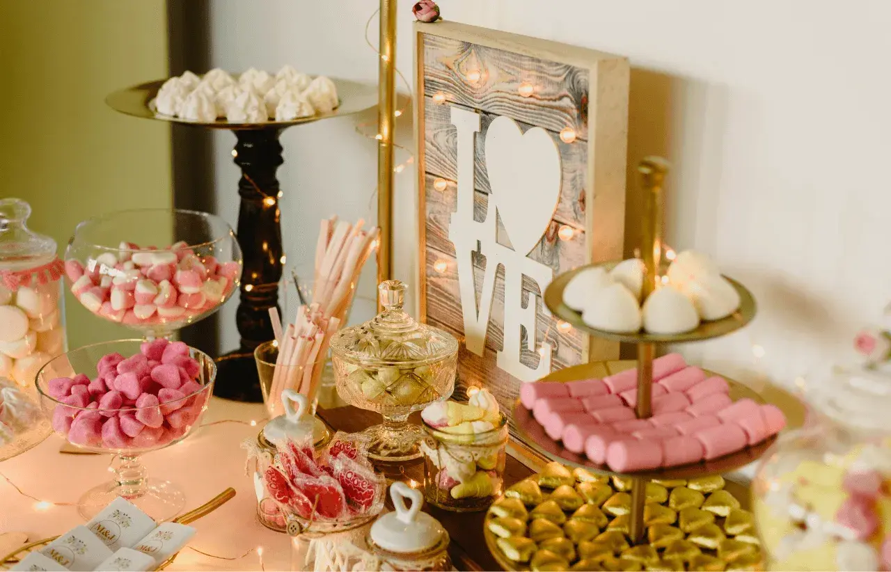 Mesa dulce con dulces variados, malvaviscos, caramelos y un cartel de "LOVE". Un candy bar original para celebrar el amor.