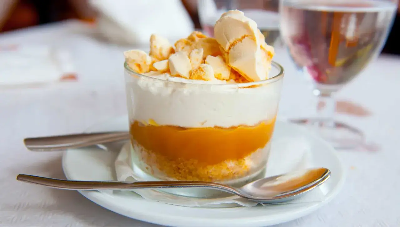 Delicioso postre en vaso con capas de galleta, dulce de leche y crema, coronado con merengue crocante. Un polvito uruguayo que invita a disfrutar.