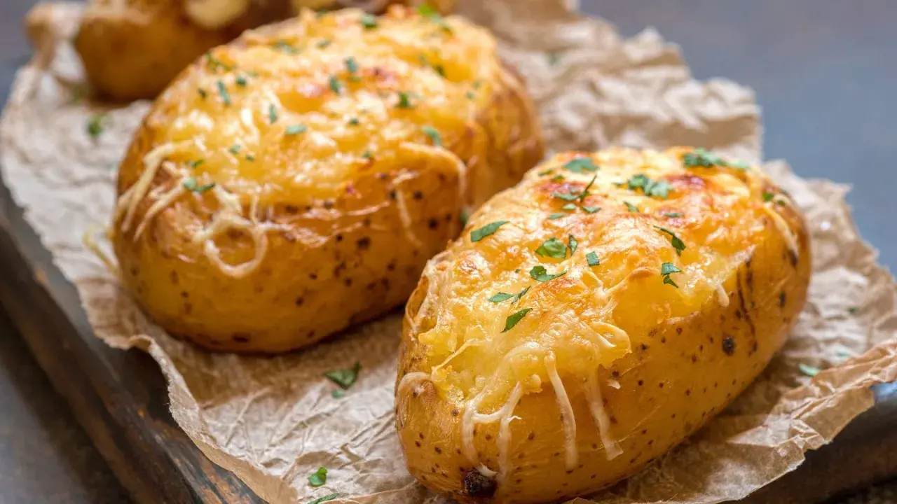 Patatas panaderas doradas y gratinadas con queso, espolvoreadas con perejil fresco.