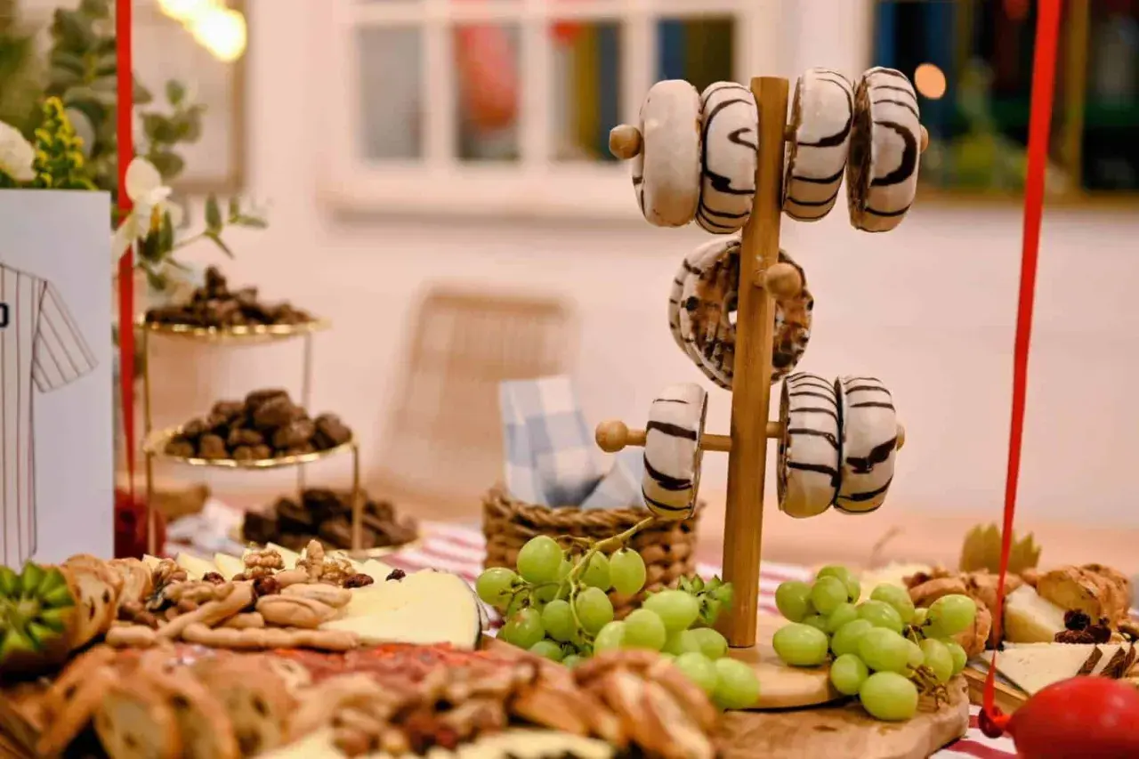 Delicioso picoteo de cumpleaños infantil con donuts, uvas, quesos y frutos secos. ¡Una mesa dulce para celebrar!