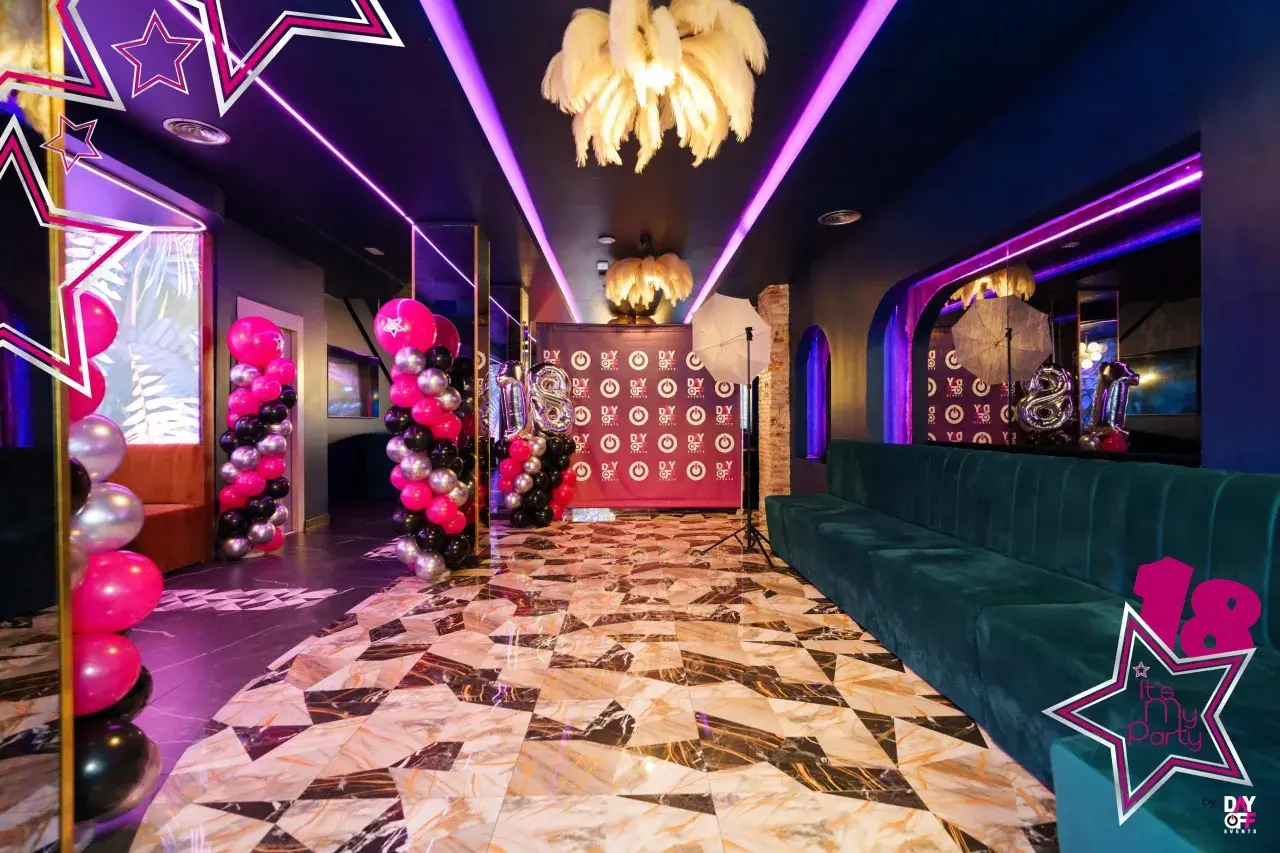 Decoración espectacular con globos rosas, negros y plateados, luces neón y un sofá verde. ¡Ideas para fiesta de 18 años mujer!