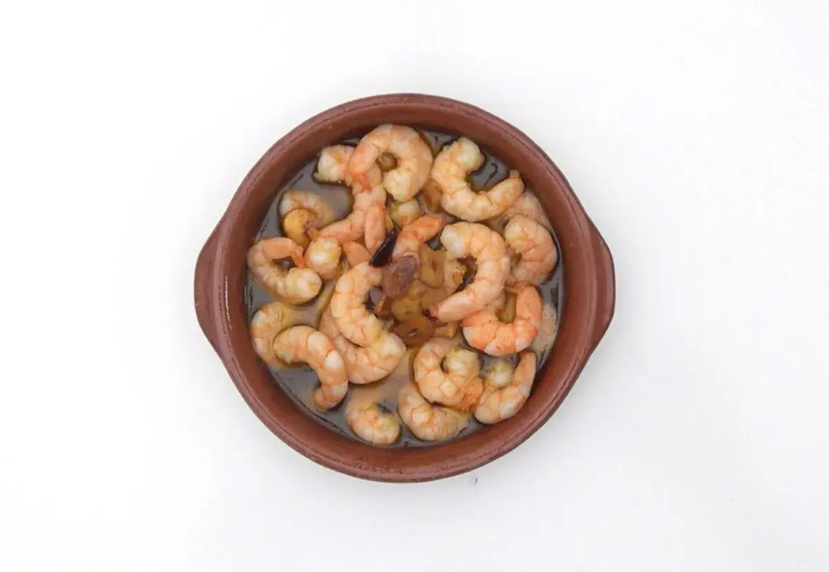 Gambas al pil pil burbujeantes en cazuela de barro, con ajo y aceite de oliva.