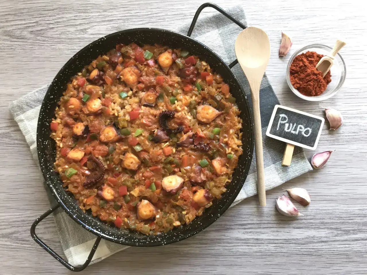 Paella de arroz con pulpo, pimientos y tomate. Ingredientes frescos listos para cocinar.