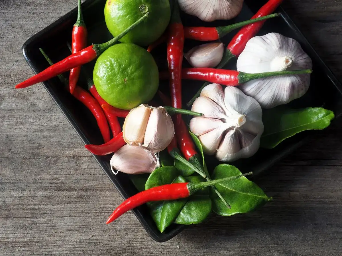 Ingredientes frescos para una vibrante salsa piri piri: chiles rojos, limones verdes, ajos y hojas aromáticas.