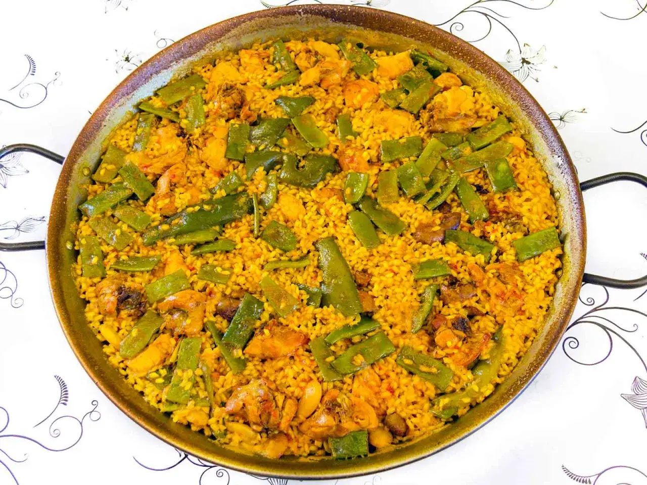 Paella mixta con arroz senia o bomba, pollo y judías verdes. Un plato tradicional español listo para disfrutar.