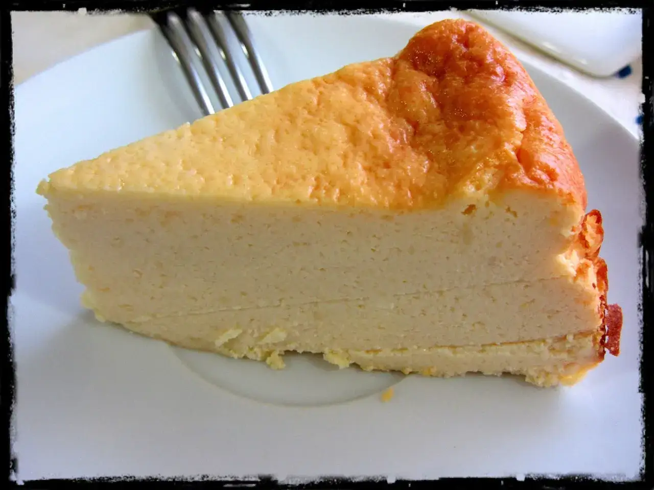 Rebanada de tarta de queso Philadelphia, cremosa y dorada, lista para disfrutar.