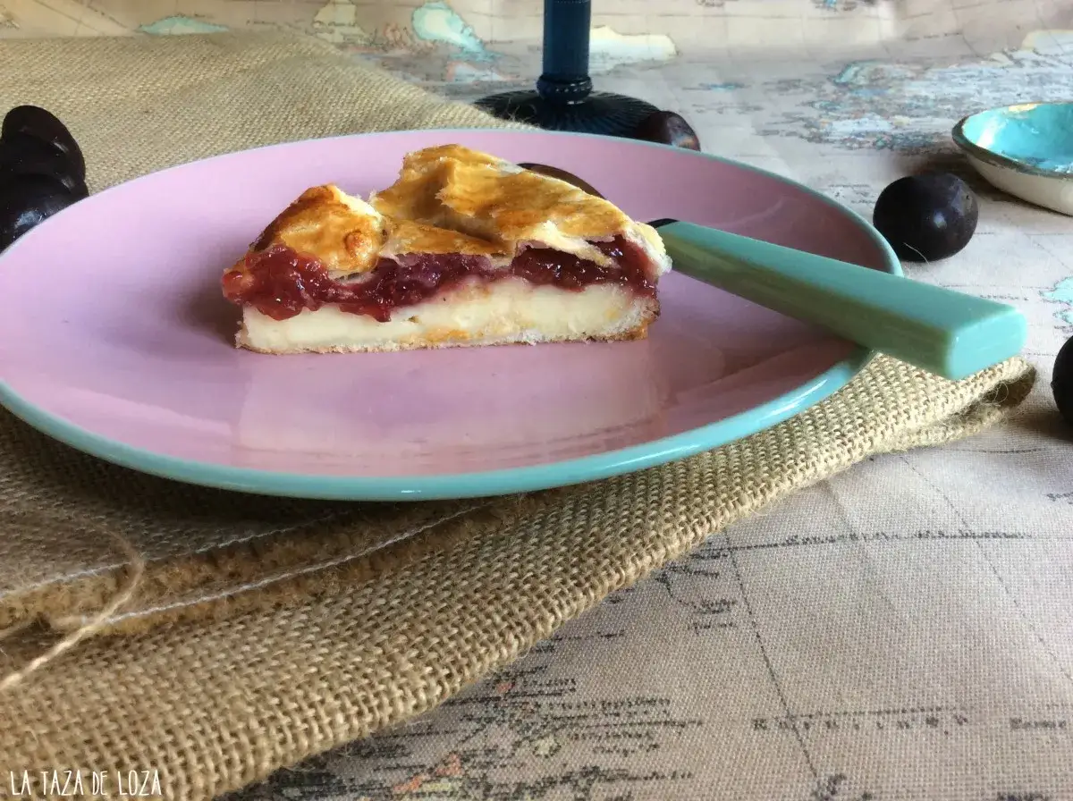 Una porci&oacute;n de pastel vasco con relleno de cerezas, sobre un plato rosa y una servilleta de arpillera.