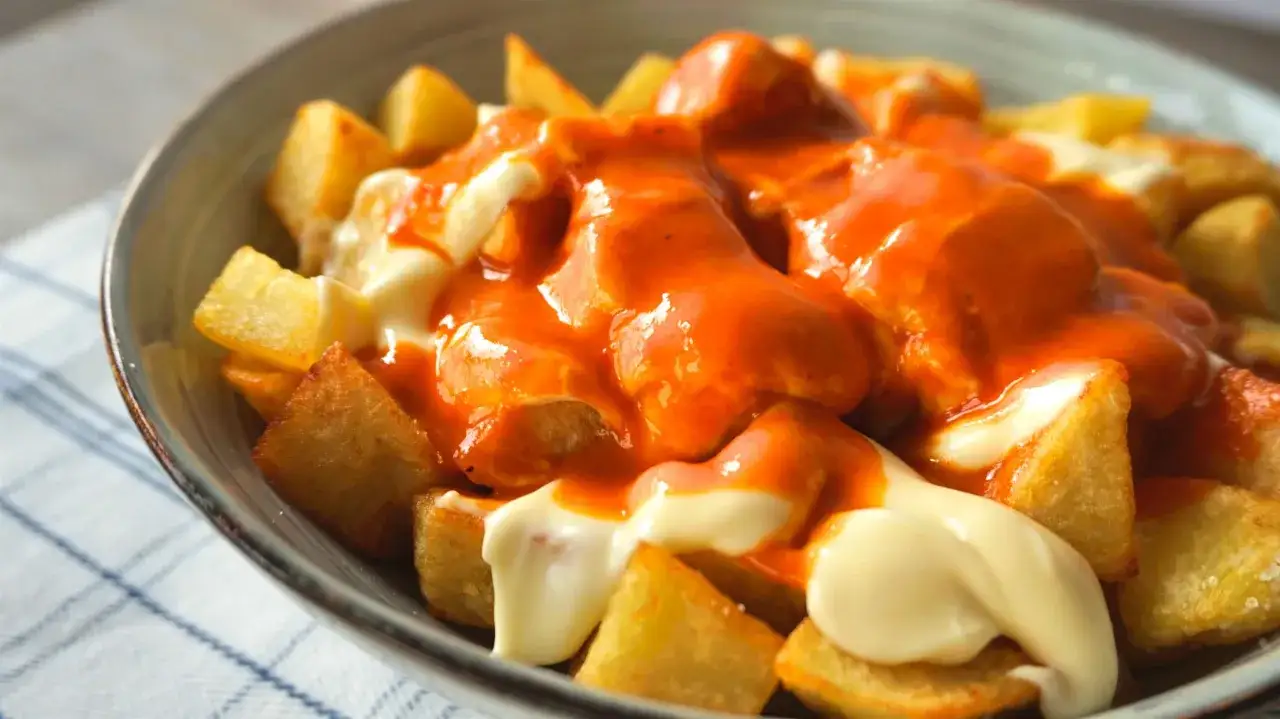 Patatas bravas crujientes ba&ntilde;adas en una cremosa mayonesa y una vibrante salsa brava, un cl&aacute;sico espa&ntilde;ol.