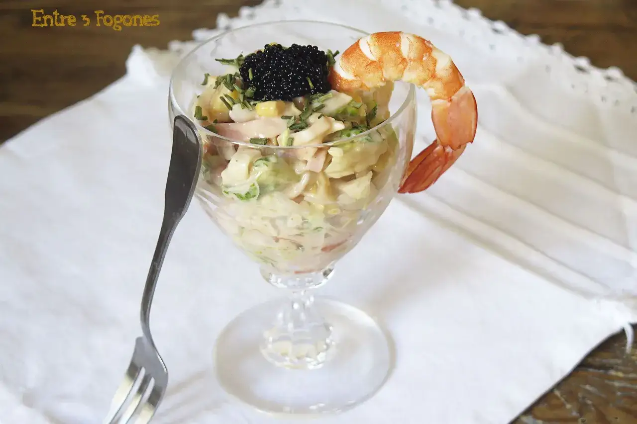 Copa de cóctel con ensalada cremosa, caviar y gamba. La salsa rosa envuelve los ingredientes, creando un bocado elegante.