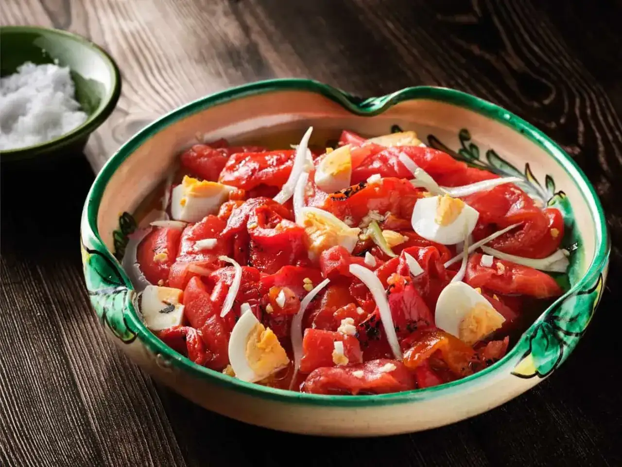 Zorongollo extremeño, una ensalada de pimientos asados, cebolla y huevo duro, servida en una cazuela de barro decorada.
