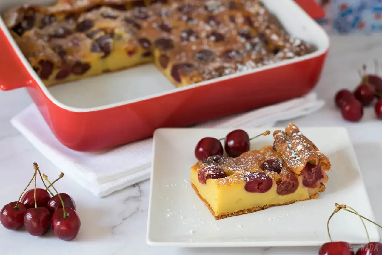 Un delicioso clafoutis de cerezas recién horneado, espolvoreado con azúcar glas.