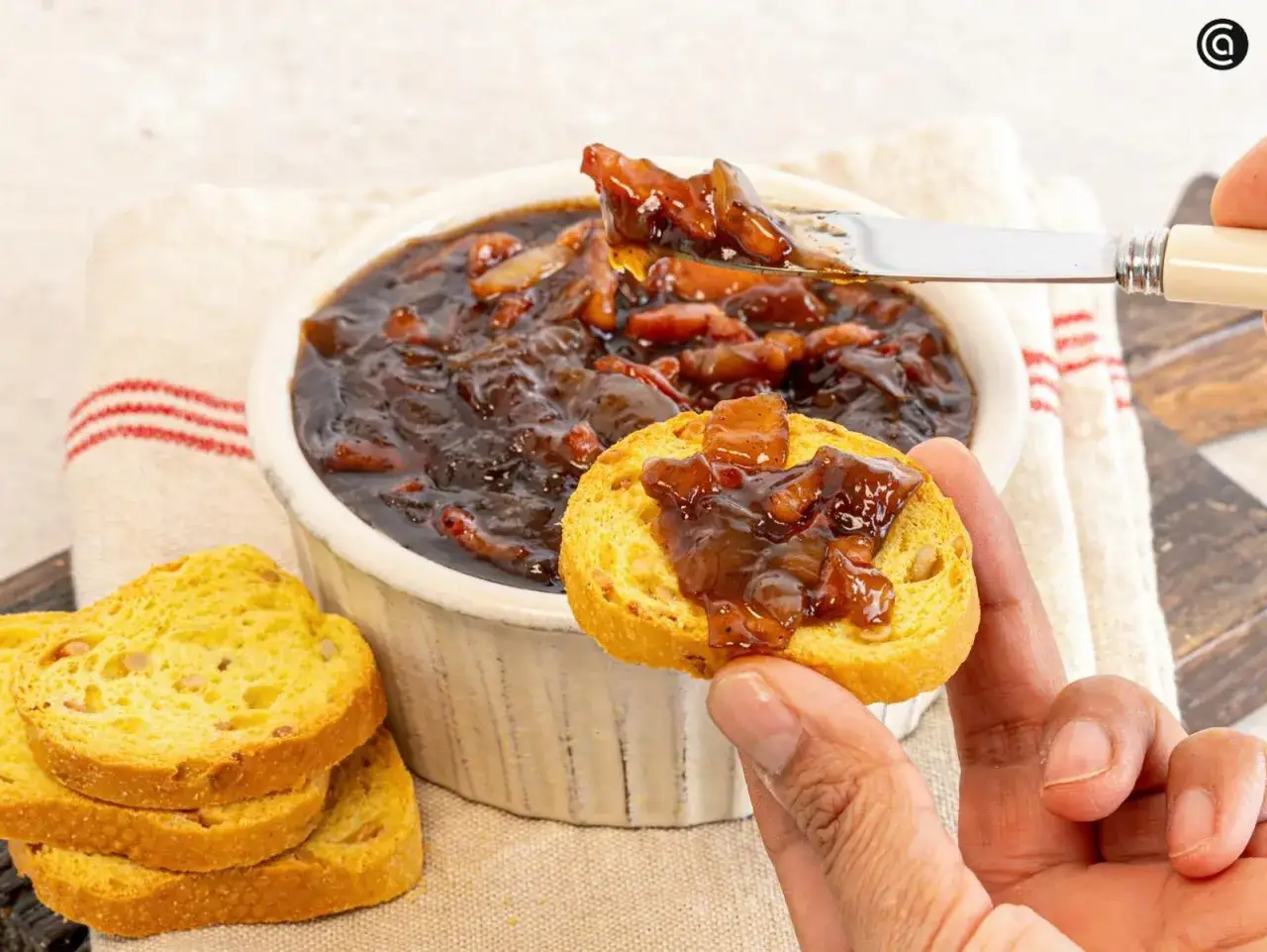 Un trozo de pan tostado con mermelada de bacon, lista para ser disfrutada.