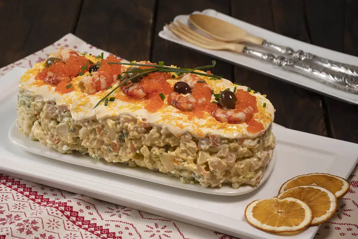 Deliciosa ensaladilla de gambas, coronada con huevas de salmón, gambas, aceitunas y ralladura de huevo. ¡Un festín visual y de sabor!