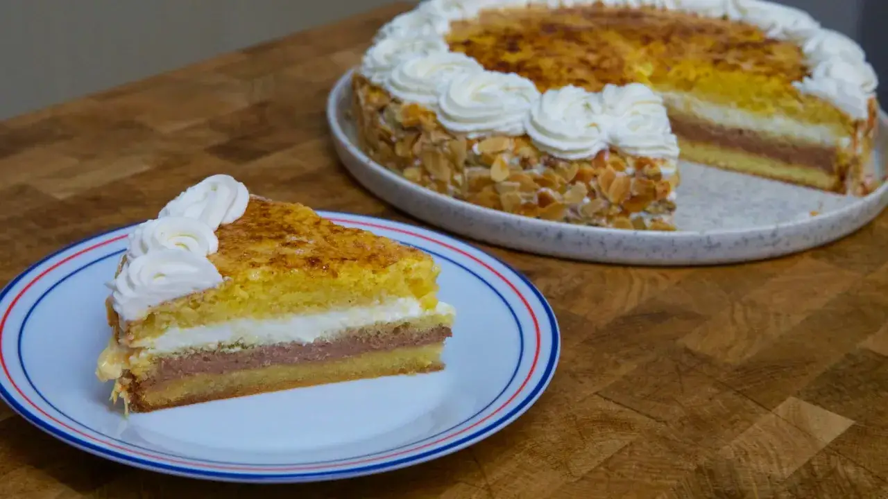 Una porción de tarta San Marcos, con bizcocho, crema de chocolate y nata montada, decorada con almendras tostadas.