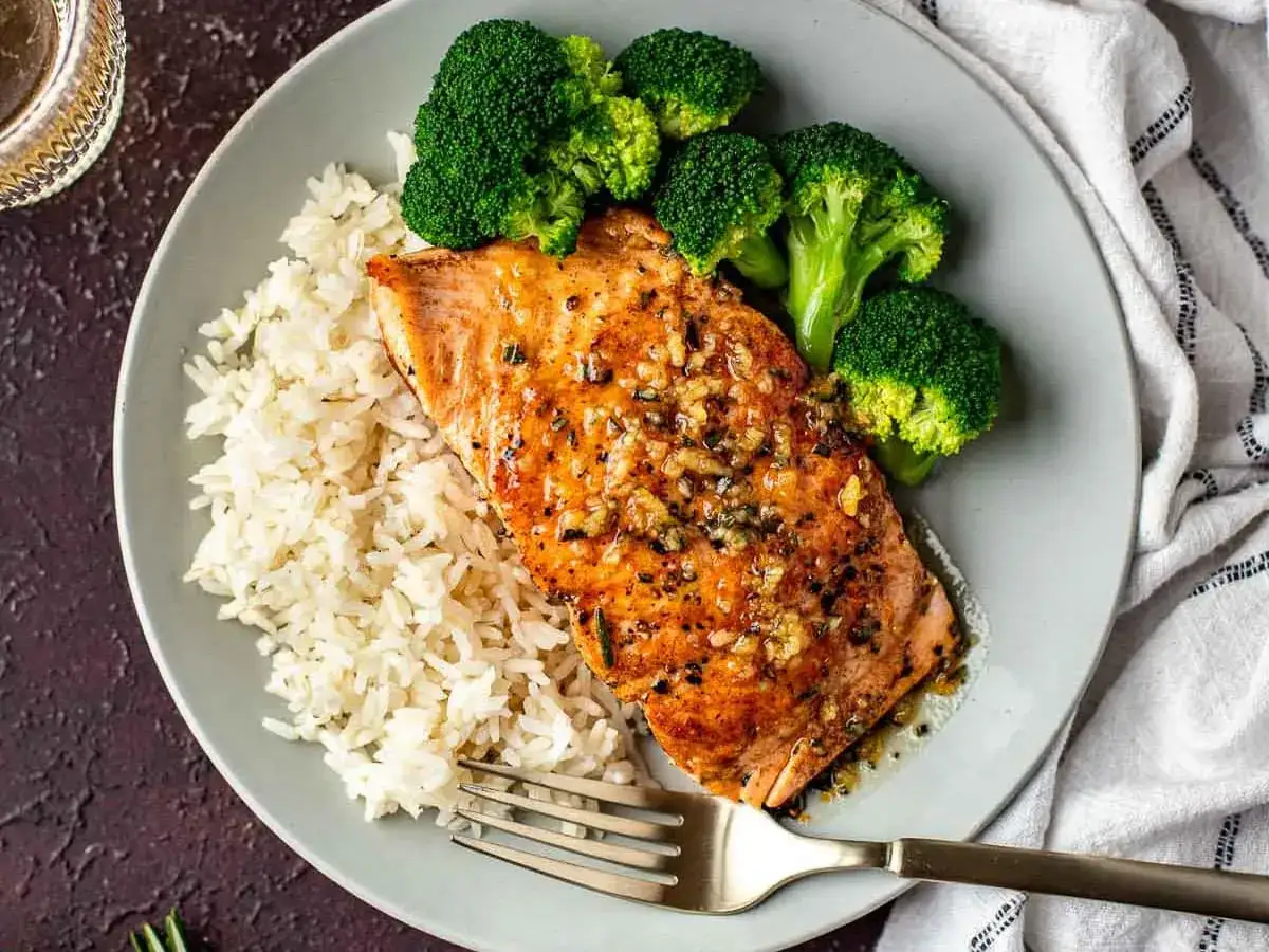 Delicioso salmón a la naranja con arroz blanco y brócoli al vapor, un plato perfecto para una cena saludable y sabrosa.