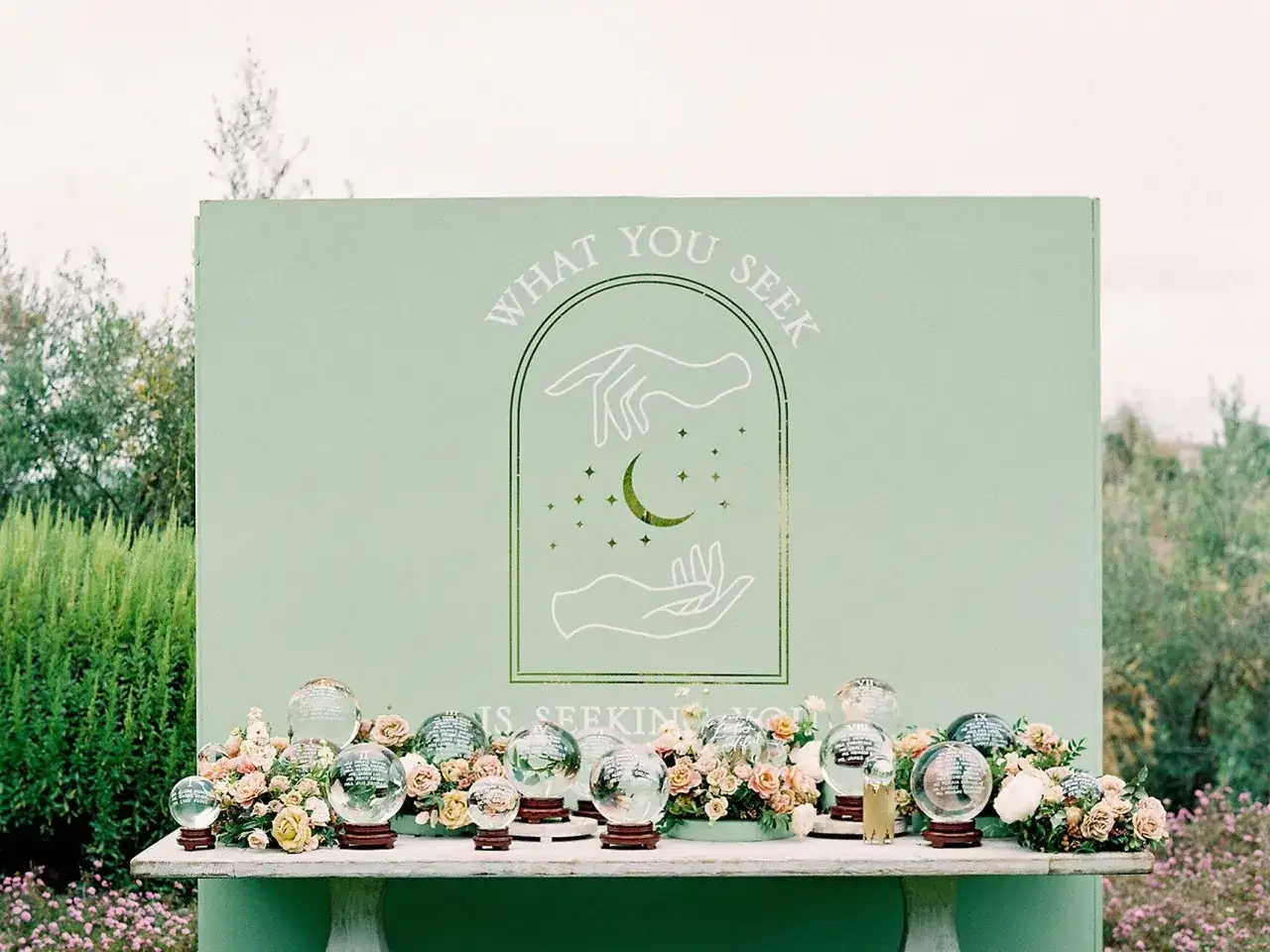 Decoración de nombres mesas boda: esferas de cristal con flores y un fondo con diseño místico.