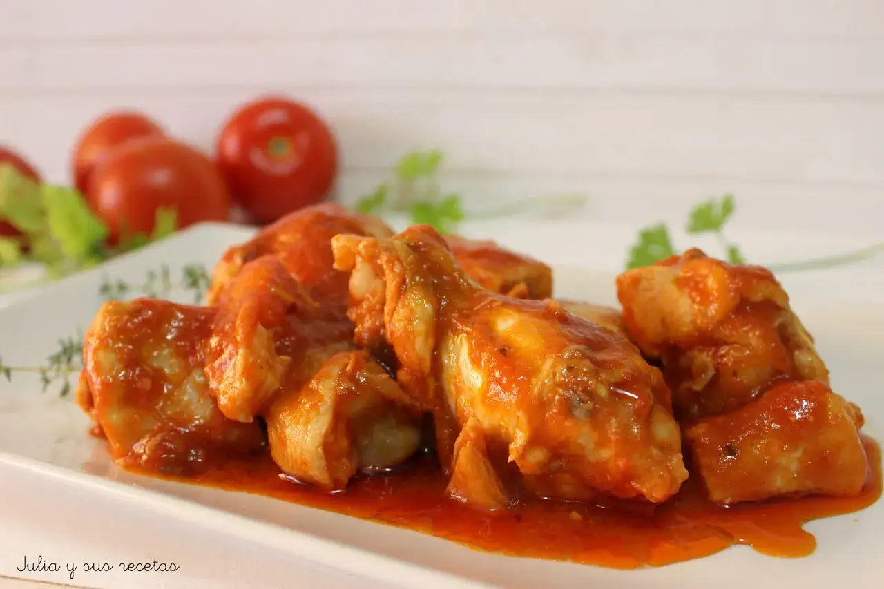 Sabroso pollo con tomate, cocinado a fuego lento hasta que esté tierno y jugoso, servido en una salsa roja vibrante.