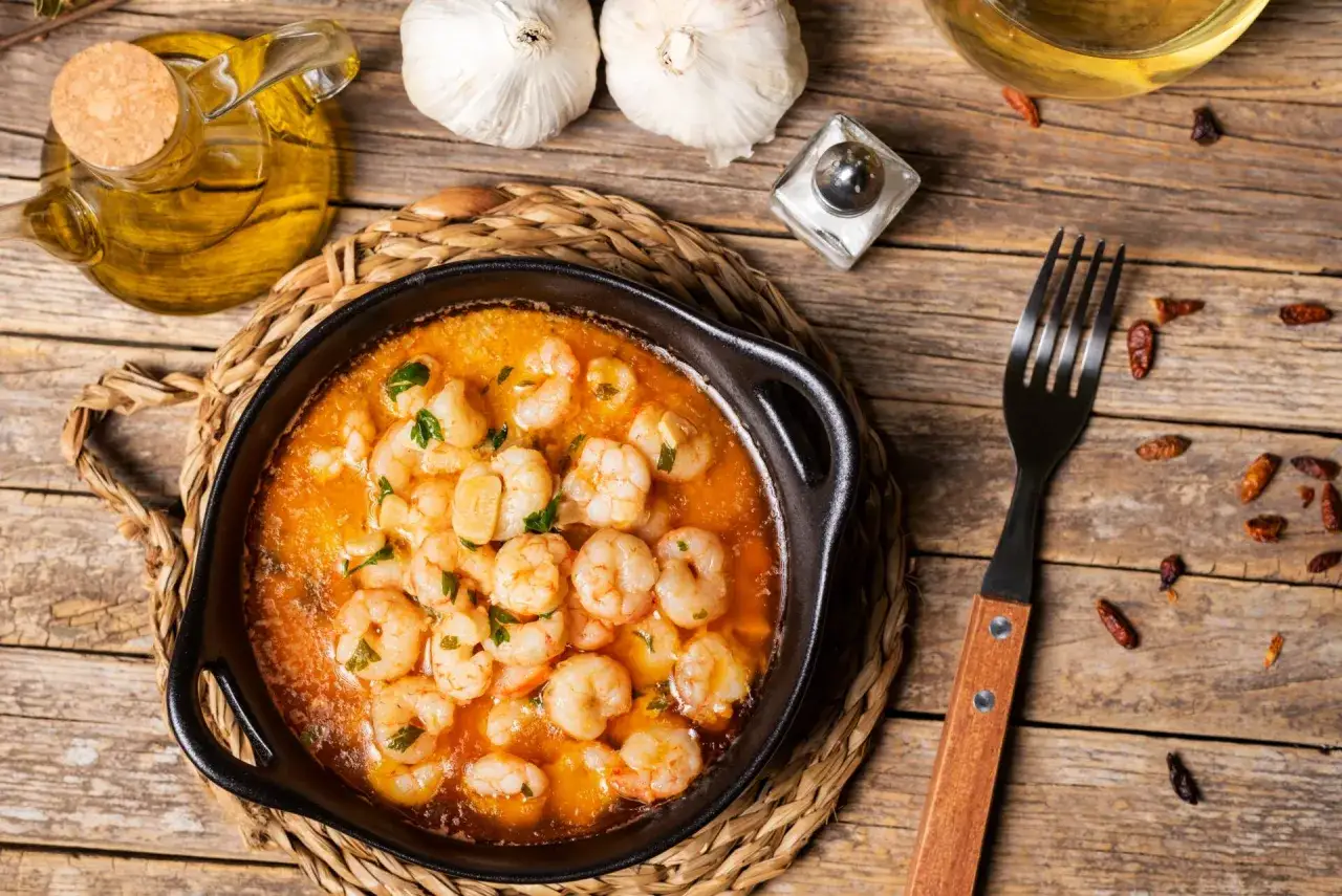 Gambas al pil pil burbujeantes en cazuela de barro, con ajo, guindillas y aceite de oliva.