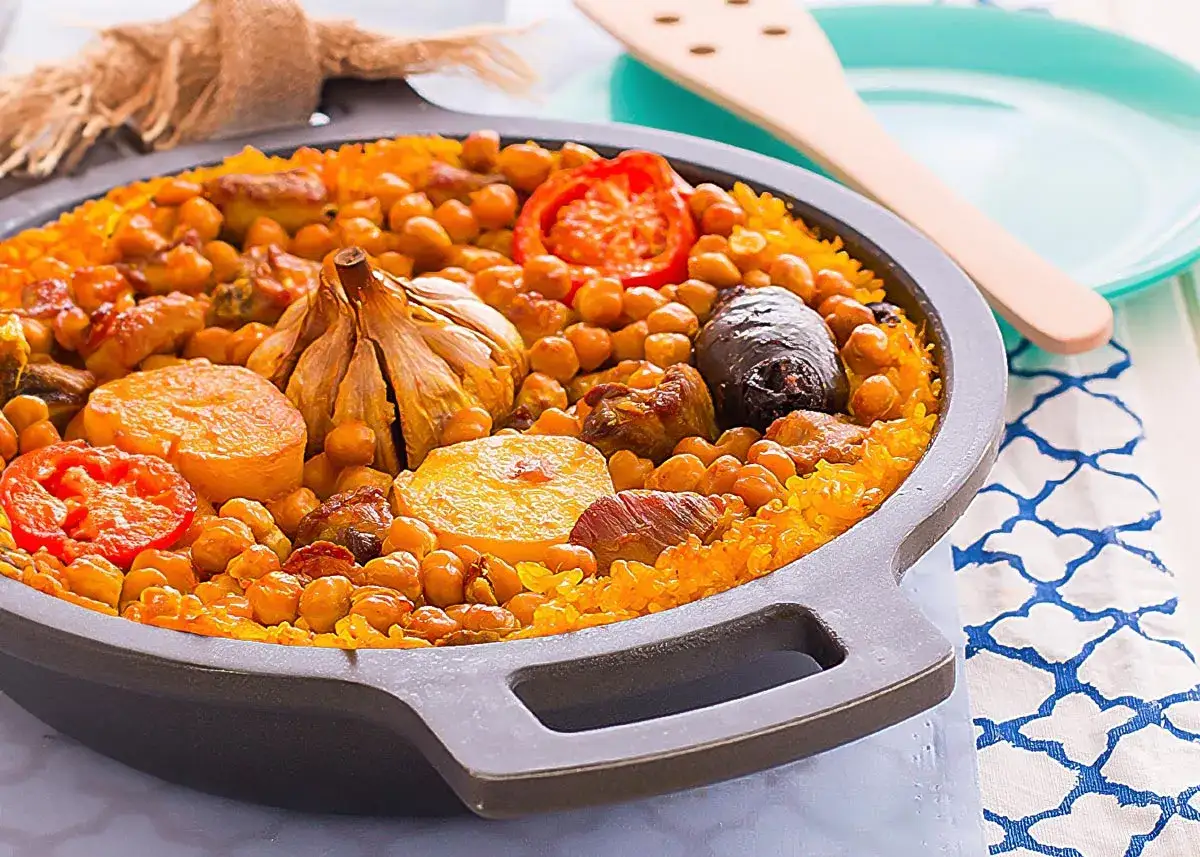 Delicioso arroz al horno con garbanzos, carne, tomate y una cabeza de ajo asada, listo para servir.